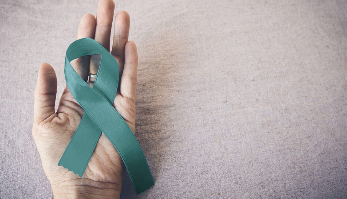 Teal Ribbon on hand, copy space toning background, Ovarian Cancer, cervical Cancer, Kidney Cancer awareness